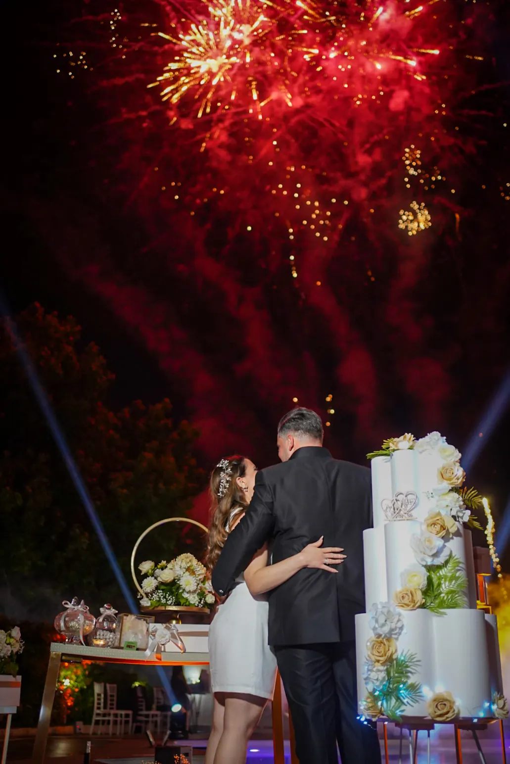Sposi di spalle sotto i fuochi d’artificio rossi e oro